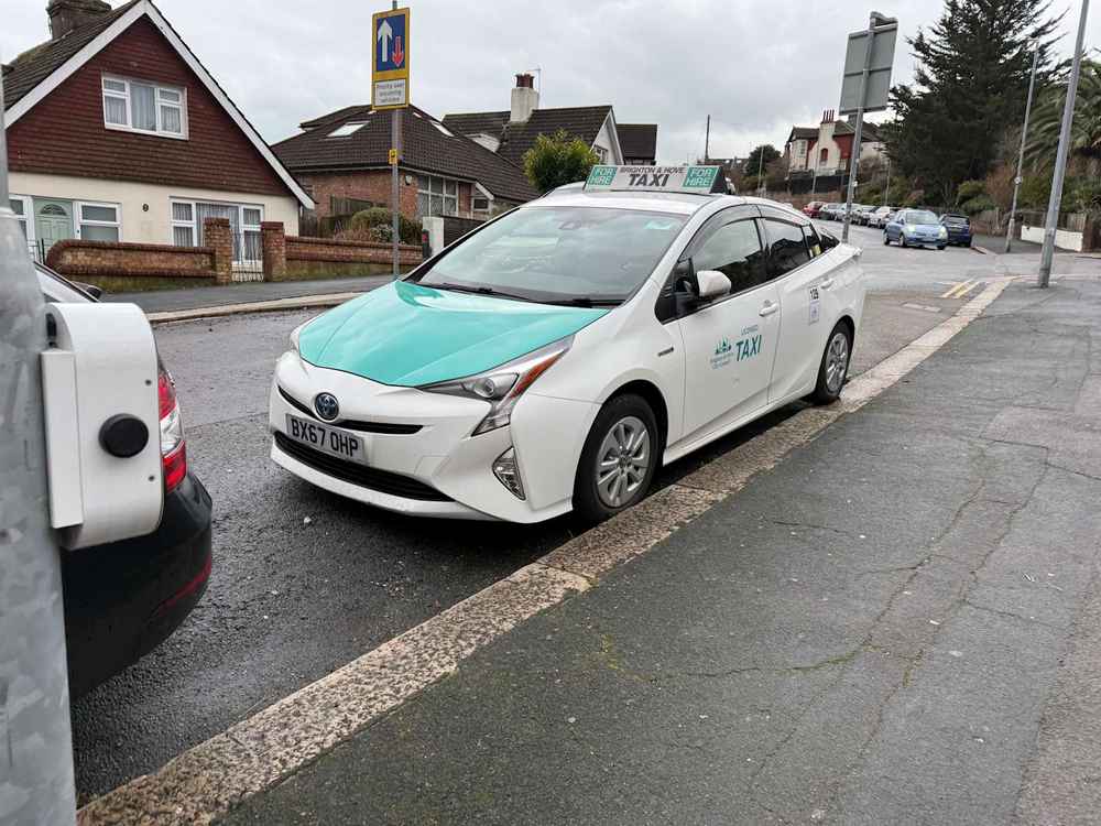 Photograph of BX67 OHP - a White Toyota Prius taxi parked in Hollingdean by a non-resident. The fifth of five photographs supplied by the residents of Hollingdean.
