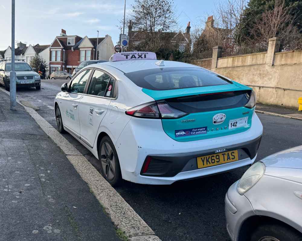 Photograph of YK69 TAS - a White Hyundai Ioniq taxi parked in Hollingdean by a non-resident. The thirteenth of thirteen photographs supplied by the residents of Hollingdean.