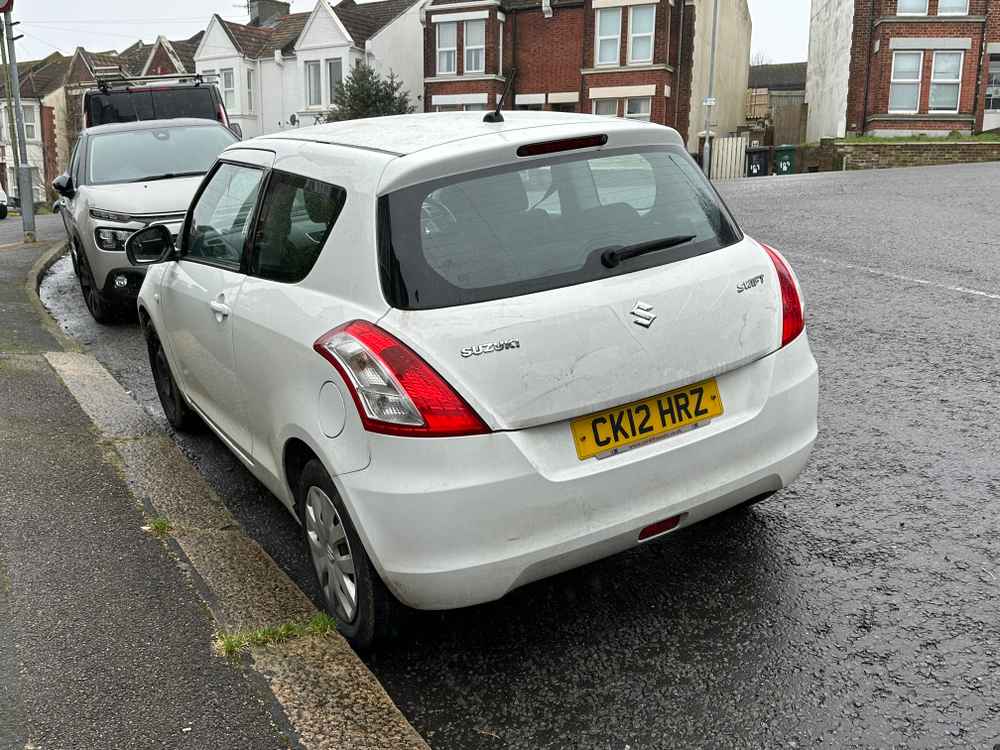 Photograph of CK12 HRZ - a White Suzuki Swift parked in Hollingdean by a non-resident. The first of five photographs supplied by the residents of Hollingdean.