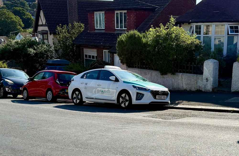 Photograph of YK69 TAS - a White Hyundai Ioniq taxi parked in Hollingdean by a non-resident. The ninth of fifteen photographs supplied by the residents of Hollingdean.