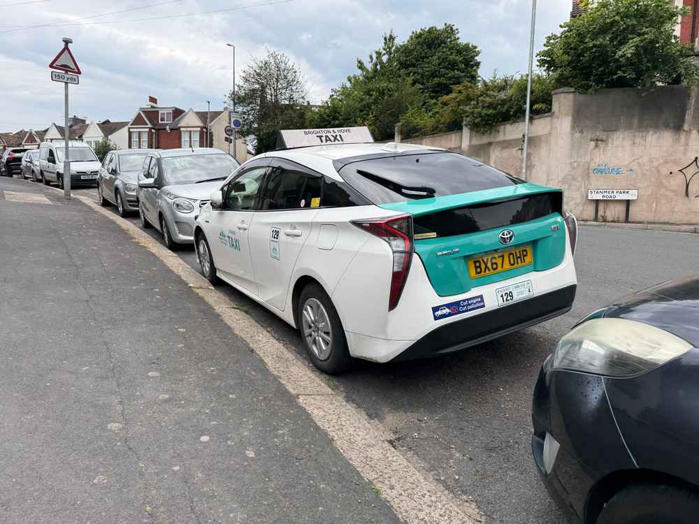 Photograph of BX67 OHP - a White Toyota Prius taxi parked in Hollingdean by a non-resident. The first of three photographs supplied by the residents of Hollingdean.