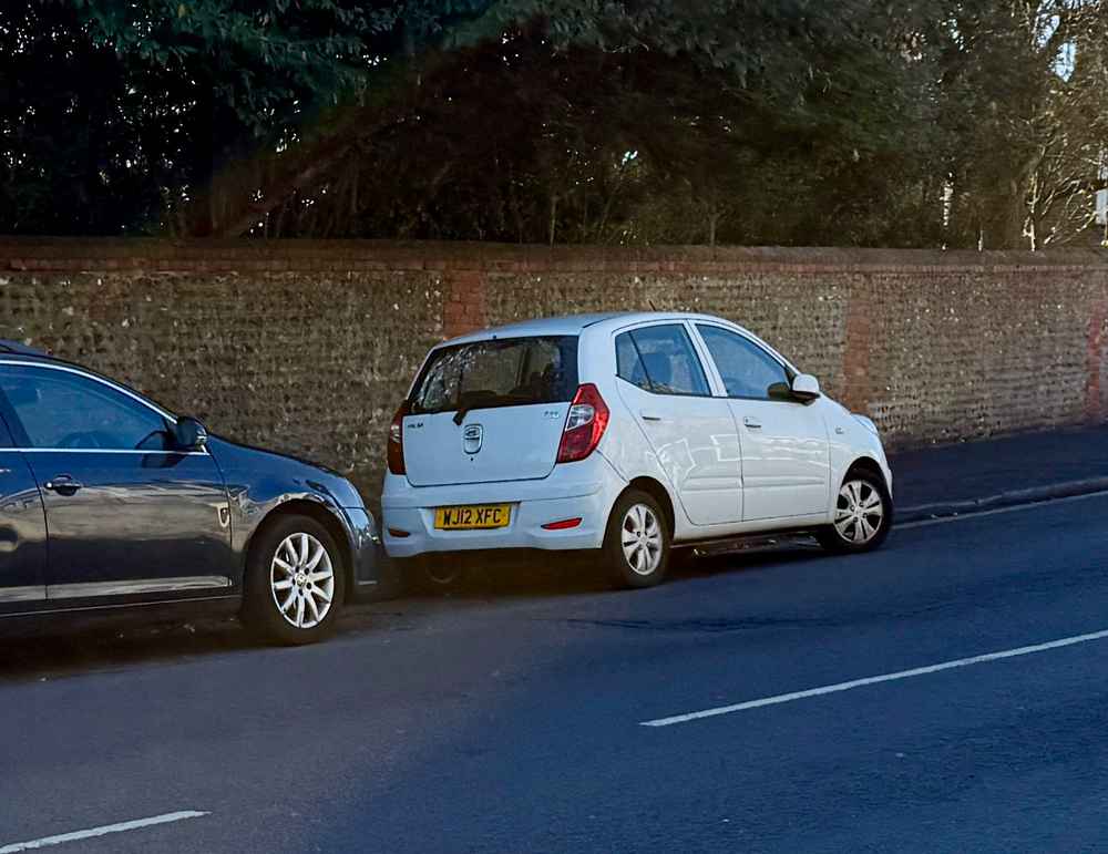 Photograph of WJ12 XFC - a White Hyundai i10 parked in Hollingdean by a non-resident, and potentially abandoned. The first of four photographs supplied by the residents of Hollingdean.