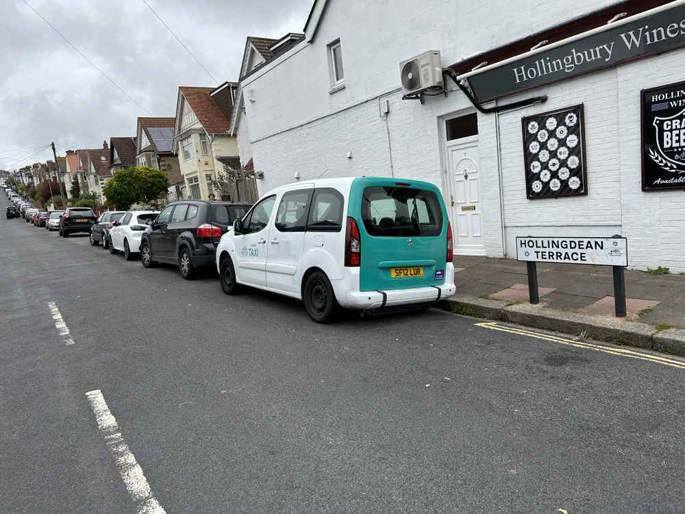 Photograph of SF12 LUR - a White Peugeot Partner taxi parked in Hollingdean by a non-resident, and potentially abandoned. The second of three photographs supplied by the residents of Hollingdean.