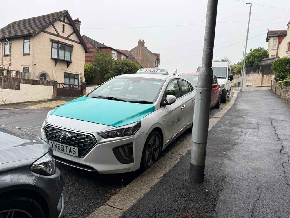 Photograph of YK69 TAS - a White Hyundai Ioniq taxi parked in Hollingdean by a non-resident. The eighth of eight photographs supplied by the residents of Hollingdean.