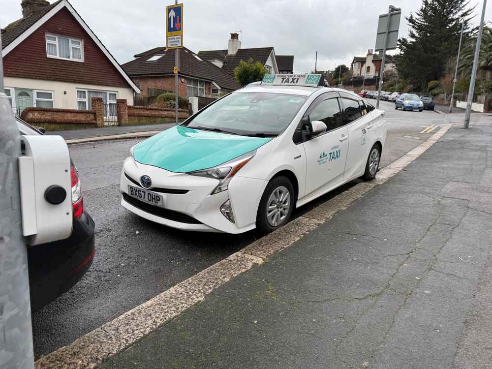 Photograph of BX67 OHP - a White Toyota Prius taxi parked in Hollingdean by a non-resident. The fifth of five photographs supplied by the residents of Hollingdean.