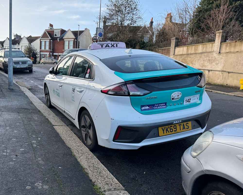 Photograph of YK69 TAS - a White Hyundai Ioniq taxi parked in Hollingdean by a non-resident. The thirteenth of fifteen photographs supplied by the residents of Hollingdean.