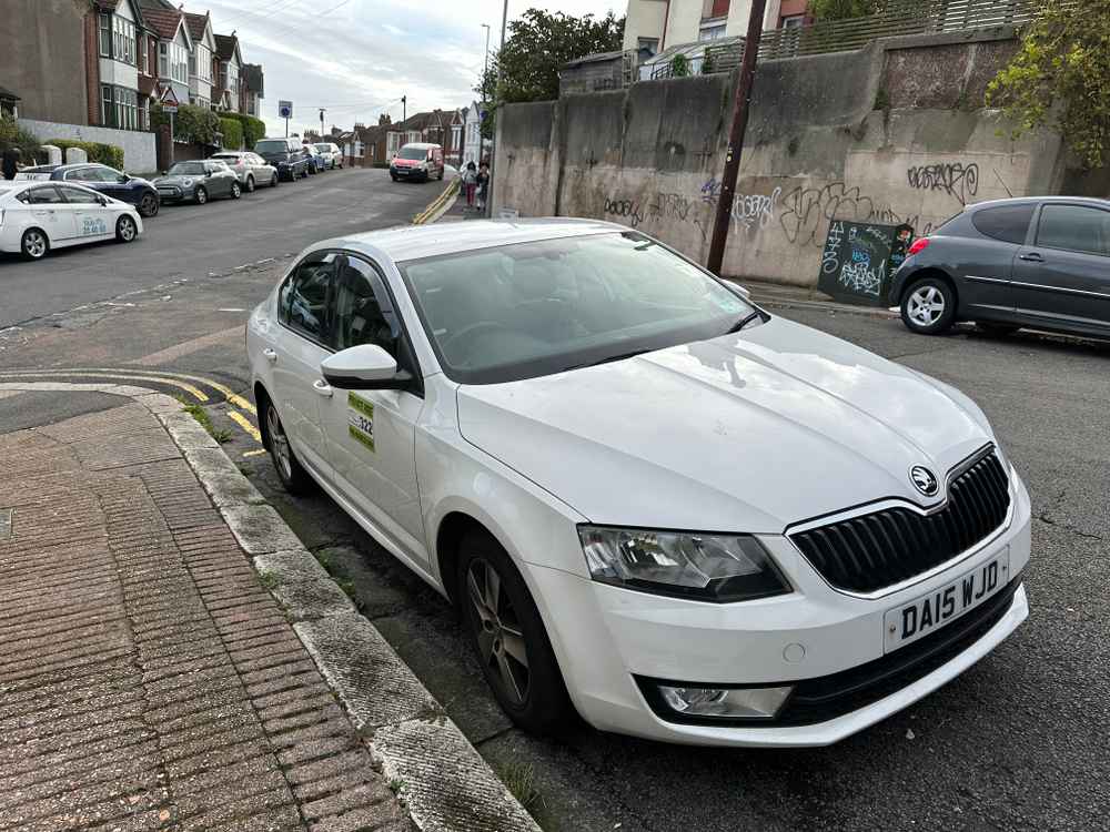Photograph of DA15 WJD - a White Skoda Octavia taxi parked in Hollingdean by a non-resident. The third of ten photographs supplied by the residents of Hollingdean.