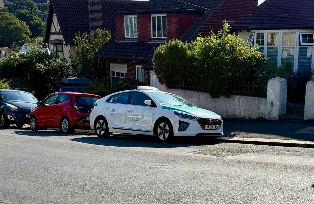 Photograph of YK69 TAS - a White Hyundai Ioniq taxi parked in Hollingdean by a non-resident. The ninth of nine photographs supplied by the residents of Hollingdean.