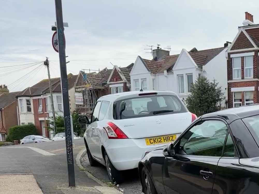 Photograph of CK12 HRZ - a White Suzuki Swift parked in Hollingdean by a non-resident. The second of five photographs supplied by the residents of Hollingdean.