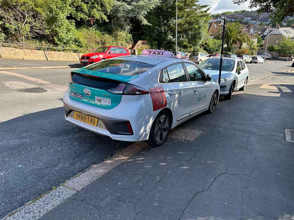 Photograph of YK69 TAS - a White Hyundai Ioniq taxi parked in Hollingdean by a non-resident. The second of fifteen photographs supplied by the residents of Hollingdean.